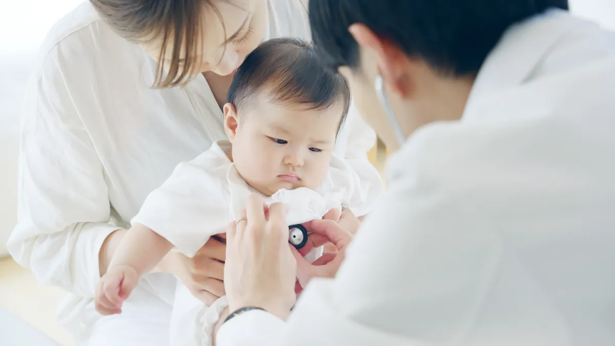 Doctor listening to a baby's chest with a stethoscope while a parent holds the child